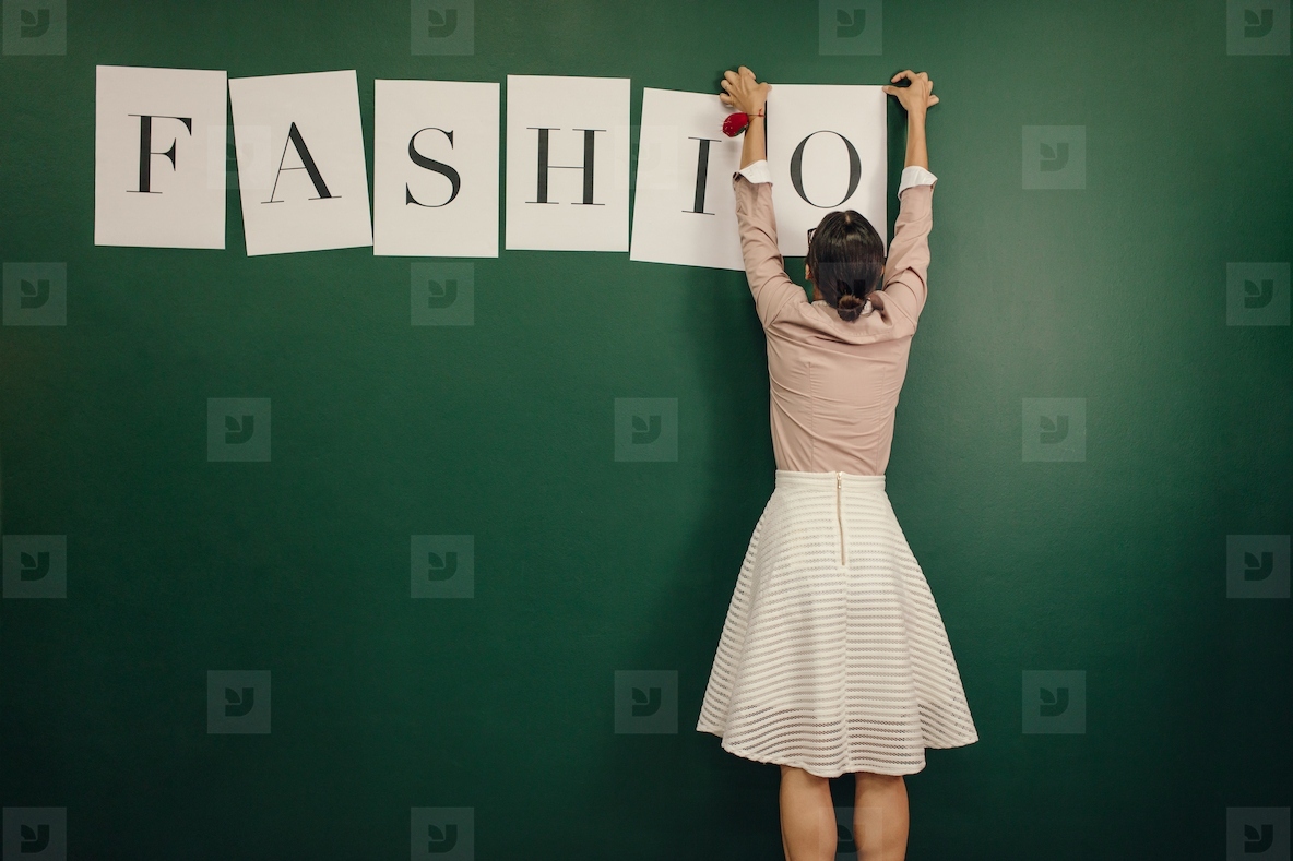 Woman arranging fashion word alphabets on wall
