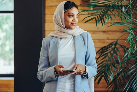 Muslim businesswoman holding a smartphone in an office