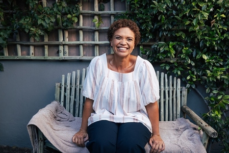 Happy mature woman on a bench  Smiling woman with short hair relaxing in backyard