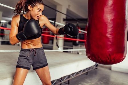 Athletic female boxer working out with a punching bag