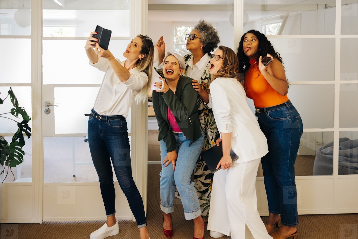 Diverse businesspeople taking a group selfie in an office