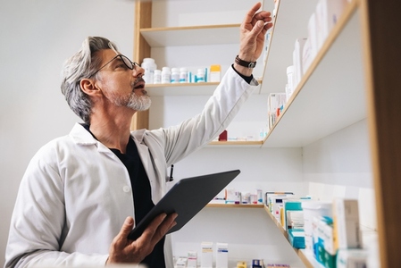 Senior pharmacist getting prescription medication from a shelf