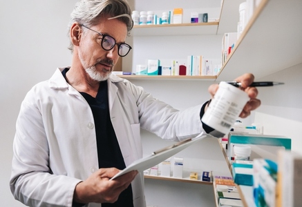 Mature pharmacist reading a medication label in a drug store