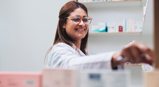 Pharmacy worker getting prescription medication from a shelf
