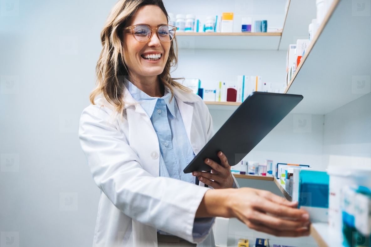 Happy pharmacist getting prescription medication from a shelf in a chemist