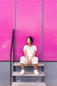 Calm Asian female near pink wall