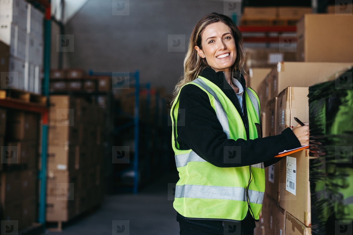Female warehouse worker smiling at the camera happily