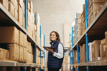 Happy young woman doing stock control in a warehouse
