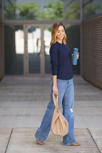 Stylish female smiling and walking on pavement