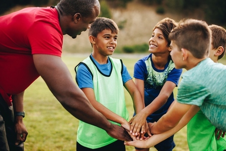 Sports trainer having a huddle with his team in a school field