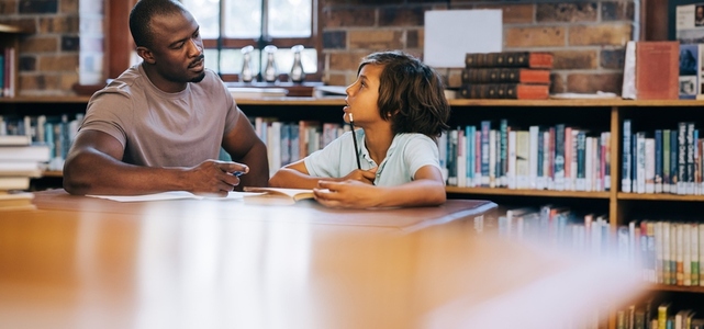 Teacher counselling a young student in a school library
