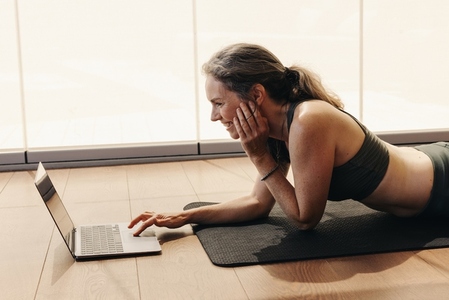 Cheerful senior woman joining a virtual yoga class on a laptop
