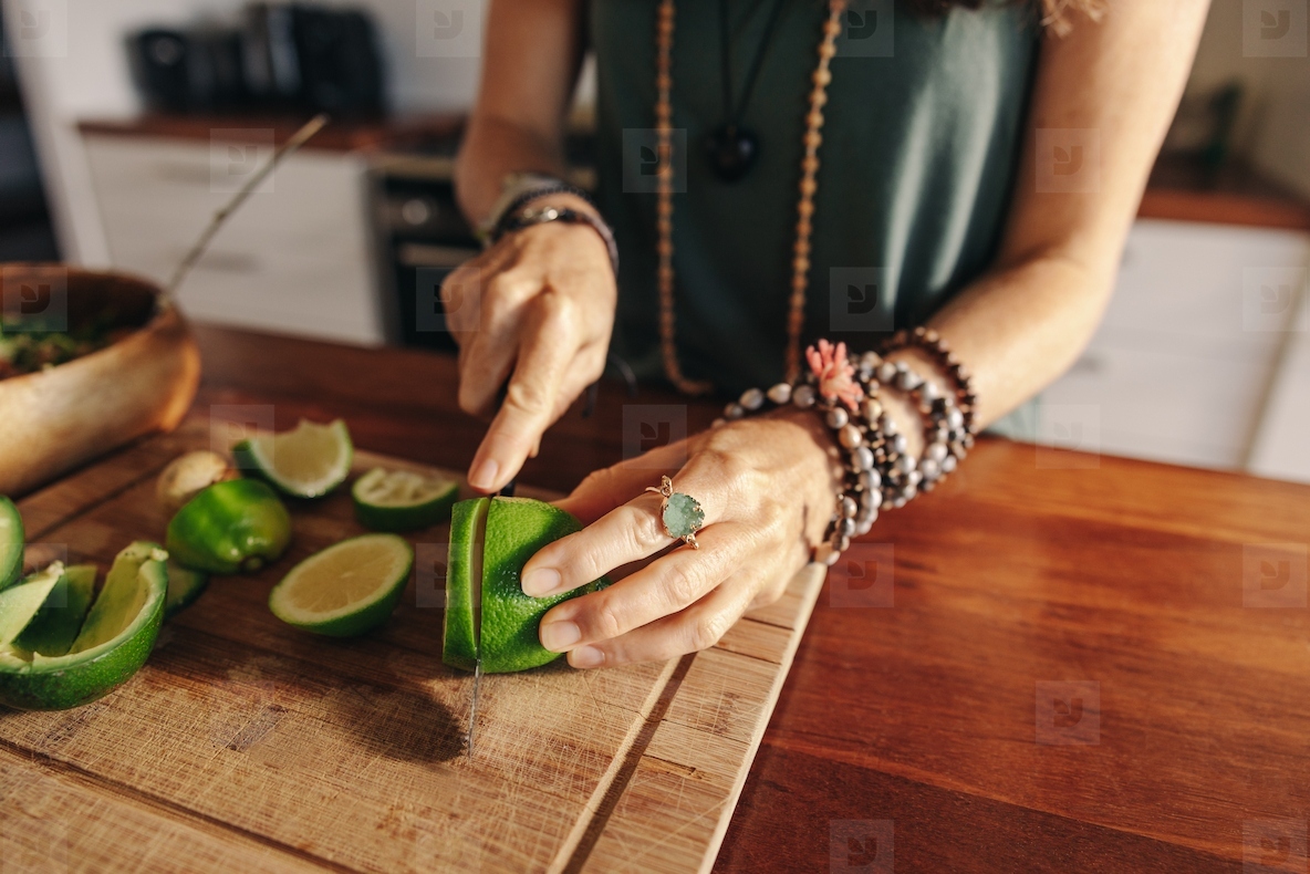 Vegetarian senior woman cutting some limes for green juice
