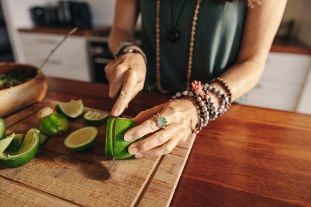 Vegetarian senior woman cutting some limes for green juice
