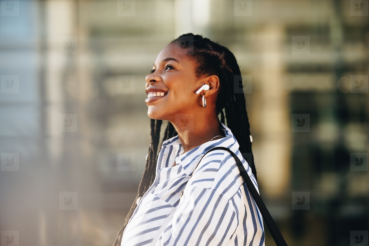 Cheerful young business woman smiling happily while walking outdoors in the city