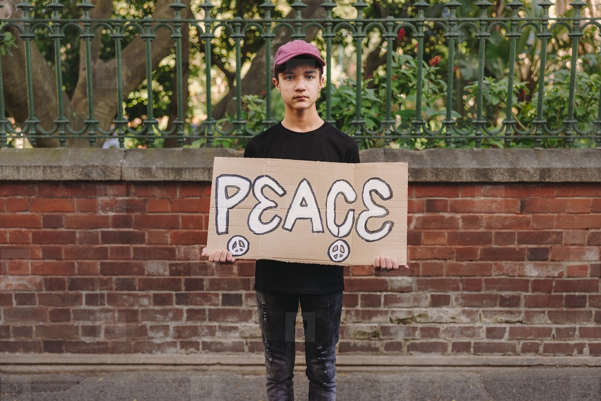 Young boy holding a peace poster outdoors
