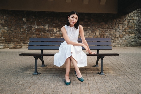 Woman in a white dress sitting on a city bench