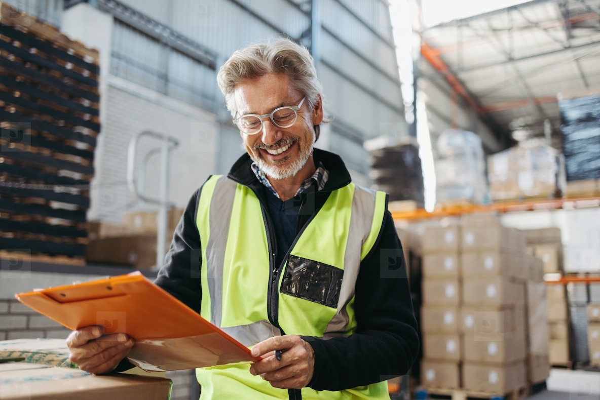 Senior warehouse manager smiling while reading a file