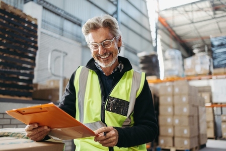 Senior warehouse manager smiling while reading a file