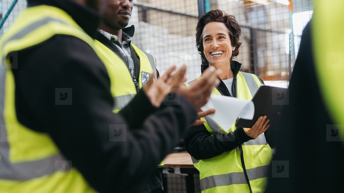 Happy mature woman having a meeting with her team in a warehouse