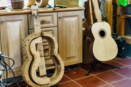 Wooden mould for making Spanish flamenco guitar  next to unfinished guitar  in luthier workshop
