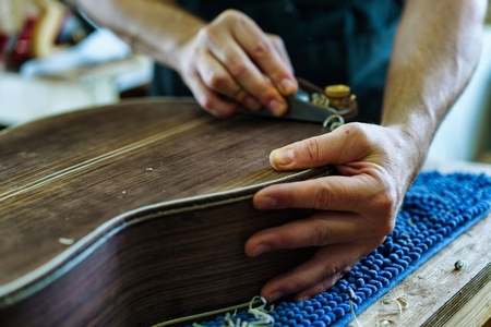 Unrecognizable Spanish flamenco guitar luthier crafting guitar part