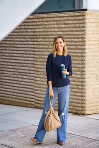 Cheerful woman with thermos and bag on street