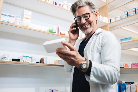 Pharmacist reading a medication label and talking on the phone