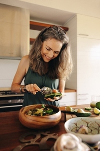 Happy vegetarian woman preparing a delicious buddha bowl at home