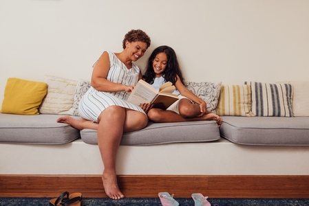 Mature woman reading to her granddaughter  Granny and a kid sitting on a couch