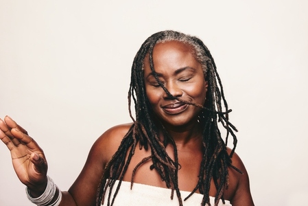 Happy woman with dreadlocks standing against a white background
