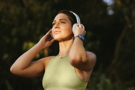 Fit woman listening to warmup music on headphones outdoors