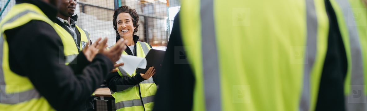 Happy mature woman having a meeting with her team in a warehouse