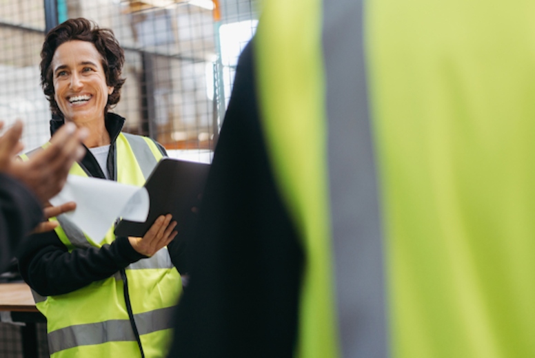 Happy mature woman having a meeting with her team in a warehouse