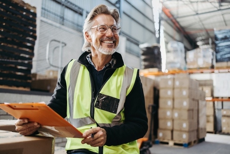 Cheerful senior man working in a distribution warehouse