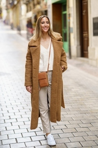 Smiling woman in stylish wear walking on street
