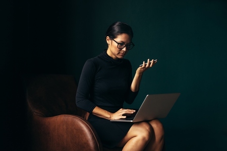 Businesswoman using mobile phone and using laptop