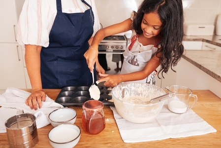 Girl using a spoon for pouring batter into molds