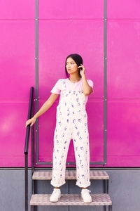 Chinese woman with blank stare and serious expression standing against pink wall of modern building
