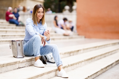Happy woman using smartphone on steps