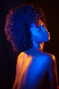 Naked African American model under neon illumination