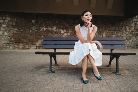 Asian woman sitting on a city bench