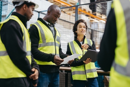 Mature woman having a discussion with her team in a warehouse