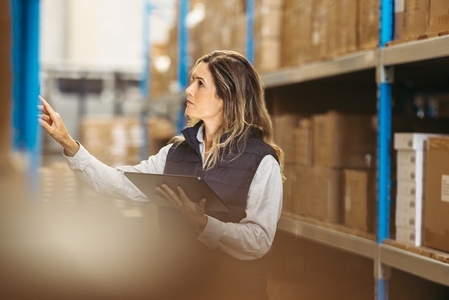 Female warehouse employee checking shipping labels using a digital tablet