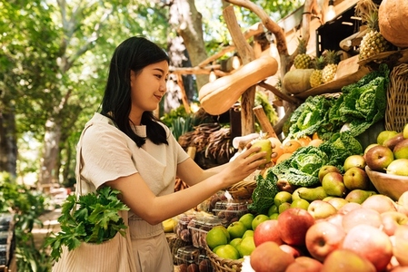 Asian woman holding pear  Young female buy organic healthy food at a local farmers market