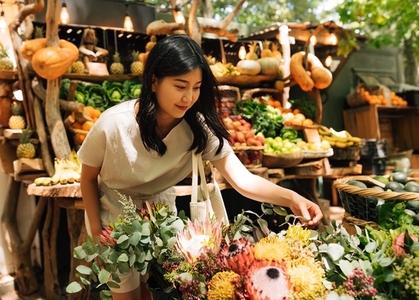 Asian woman in casual choosing flowers on outdoor market