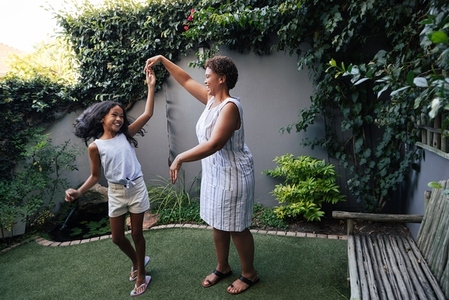 Happy girl dancing with her grandmother on backyard