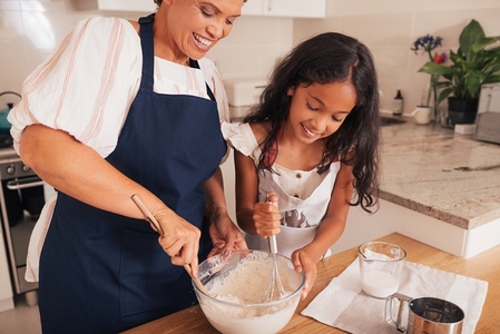 Girl and her grandma mix batter together in a glass bowl
