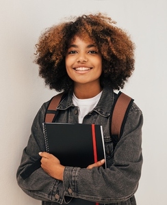 Cheerful girl with curly hair holding a books wearing backpack
