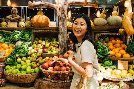 Laughing Asian woman on an outdoor market  Smiling female buying organic food